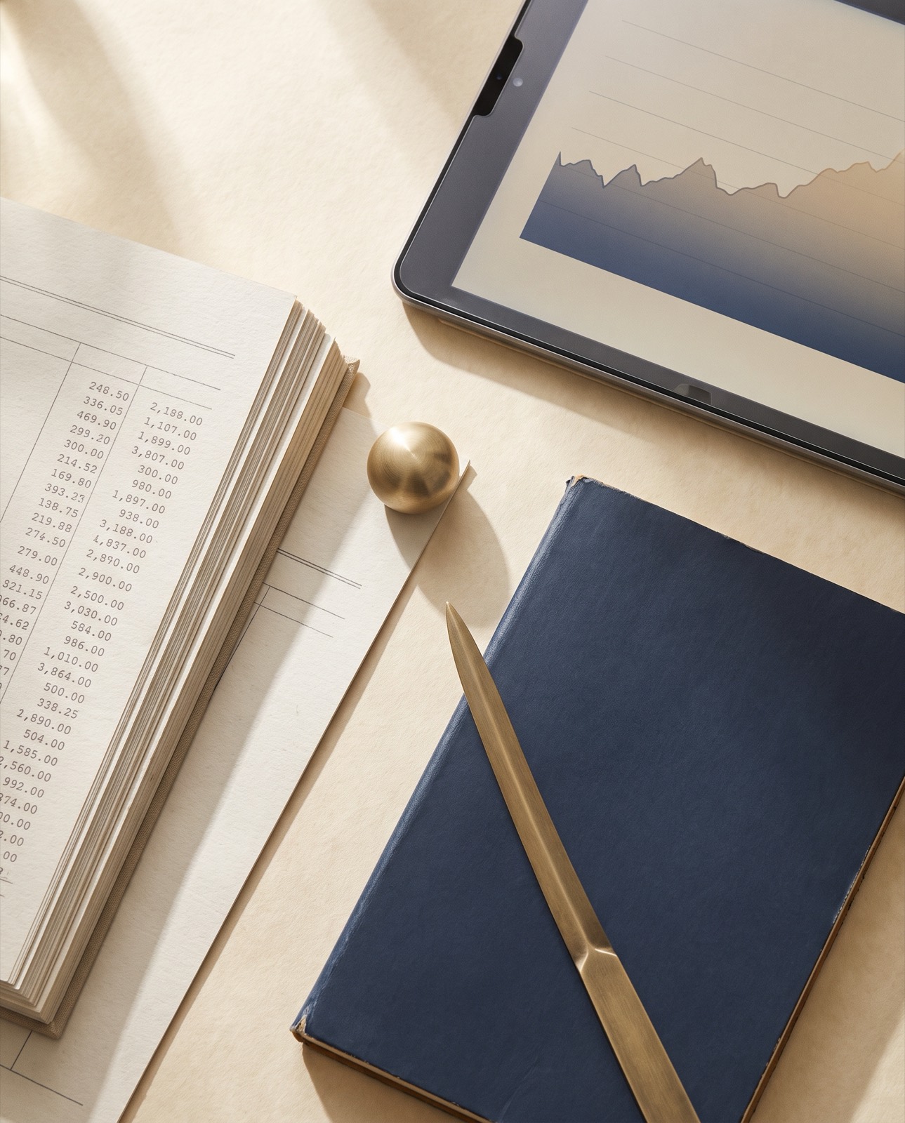 Printed transaction ledgers, a navy notebook and a brass letter opener on a cream desk